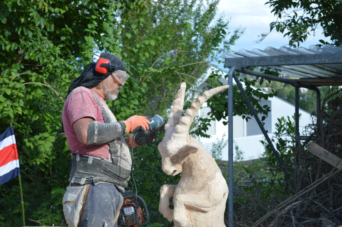 Ein Mann sägt einen Steinbock aus Holz.
